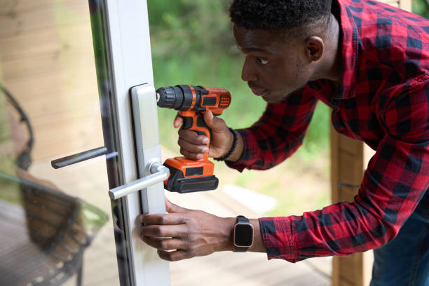 Young repairman is repairing a windows and glass door, he is using a screwdriver. A young man doing installations of Windows and doors